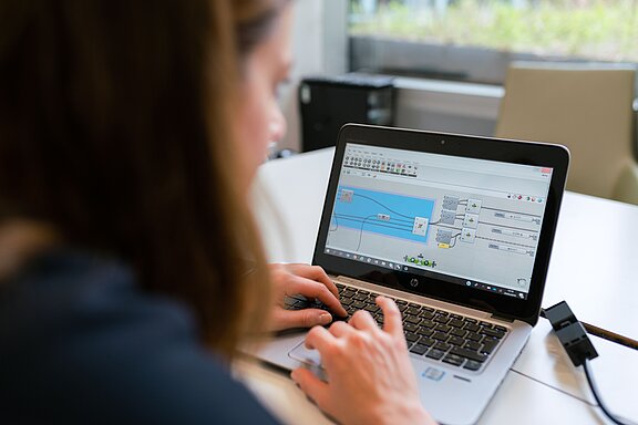 Eine Frau sitzt am Laptop, auf diesem ist eine Automatisierung zu sehen, Symbolbild für KI als Werkzeug